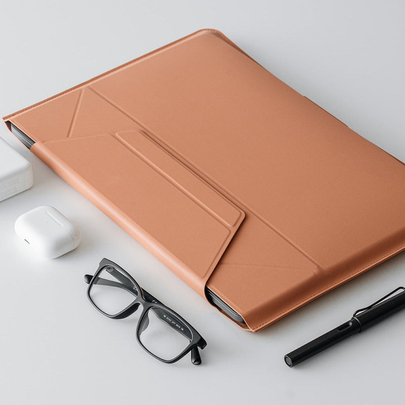 MOFT - Laptop Carry Sleeve 輕薄三合一 隱形立架筆電包 in a stylish tan color, placed on a simple desk with glasses and a pen.