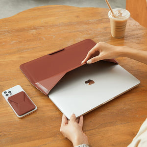 MOFT - Laptop Carry Sleeve 輕薄三合一 隱形立架筆電包 being opened to reveal a silver laptop on a wooden table.